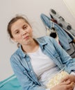 Young teenage girl sitting cross-legged on bed eating popcorn Royalty Free Stock Photo