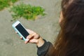 A young teenage girl is sitting outside on the street and holding a cell phone with a blank screen in her hands. Mobile phone in h Royalty Free Stock Photo