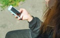 A young teenage girl is sitting outside on a Sunny day and holding a cell phone with a blank screen in her hands. Communication on Royalty Free Stock Photo