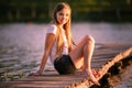 Young teenage girl sitting on pier in sunset beams Royalty Free Stock Photo