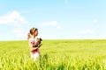 Young girl in wheat field holding dog contemplating the nature