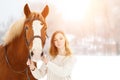 Young teenage happy girl with horse in winter park