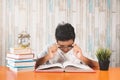 Young teenage reading books while fixing his spectales for focus