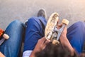 Young teenage skaters sitting together in a skate park with skateboards in hand - Extreme sport, friendship, youth concept -