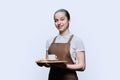 Young teenage female waitress holding tray with cup of coffee, on white background