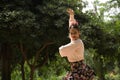 Young teenage woman in pink shirt, black skirt with flowers and pink carnations in her hair, dancing flamenco surrounded by Royalty Free Stock Photo