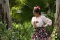 Young teenage woman in pink shirt, black skirt with flowers and pink carnations in her hair, dancing flamenco surrounded by Royalty Free Stock Photo