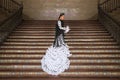 Young teenage woman in white dance suit with black polka dots, black shawl and green carnations in her hair doing flamenco poses Royalty Free Stock Photo