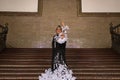 Young teenage woman in white dance suit with black polka dots, black shawl and green carnations in her hair doing flamenco poses Royalty Free Stock Photo