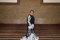 Young teenage woman in white dance suit with black polka dots, black shawl and green carnations in her hair doing flamenco poses Royalty Free Stock Photo