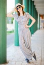 Young teenaged girl in jumpsuit dress posing at colonnade