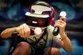Young teenager boy using a Virtual reality headset with goggles and hands motion controllers in playing game zone. Modern