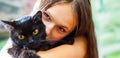 Young teenager brunette girl holding in her arms black cat. Royalty Free Stock Photo