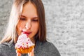 Young teenager brunette girl with long hair eating cream cake on gray wall background Royalty Free Stock Photo