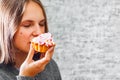 Young teenager brunette girl with long hair eating cream cake on gray wall background Royalty Free Stock Photo