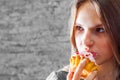 Young teenager brunette girl with long hair eating cream cake on gray wall background Royalty Free Stock Photo