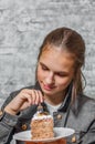 Young teenager brunette girl with long hair eating slice cake dessert on gray wall background Royalty Free Stock Photo