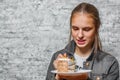 Young teenager brunette girl with long hair eating slice cake dessert on gray wall background Royalty Free Stock Photo