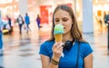 Young teenager brunette girl with long hair eating tasty cone ice cream in shopping mall Royalty Free Stock Photo