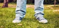 Young teenager foot and legs with blue sneakers and jeans on the green grasses of a garden. Youth fashion Royalty Free Stock Photo