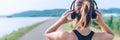 Young teenager girl adjusting wireless headphones before starting jogging and listening to music. Web page header cropping