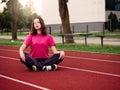 Young teenager girl doing stretching exercises on a running track. Selective focus. The model is slim body type. Light and airy