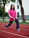 Young teenager girl doing stretching exercises on a running track. Selective focus. The model is slim body type. Light and airy