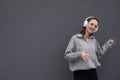 A young teenager girl listens to music with headphones, dressed in a black jacket and jeans, dances to the music and sings songs Royalty Free Stock Photo