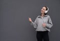 A young teenager girl listens to music with headphones, dressed in a black jacket and jeans, dances to the music and sings songs Royalty Free Stock Photo