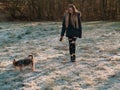 Young teenager girl with long hair. Walking her small friend Yorkshire terrier in a park.