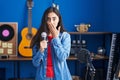 Young teenager girl singing song using microphone covering mouth with hand, shocked and afraid for mistake Royalty Free Stock Photo