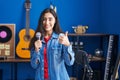 Young teenager girl singing song using microphone smiling happy and positive, thumb up doing excellent and approval sign Royalty Free Stock Photo