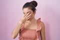 Young teenager girl standing over pink background tired rubbing nose and eyes feeling fatigue and headache