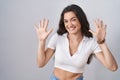 Young teenager girl standing over white background showing and pointing up with fingers number ten while smiling confident and Royalty Free Stock Photo