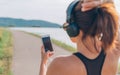 Young teenager girl starting jogging and choosing favorite music composition to listening using smartphone and wireless
