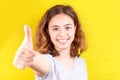 Young teenager girl with thumb up smiling at camera. Positive attitude