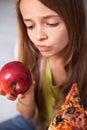 Young teenager girl undecided between healthy fresh apple and ap Royalty Free Stock Photo