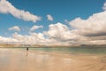 Young teenager girl walking on a warm sand of Gurteen beach, county Galway, Ireland. Warm sunny day. Cloudy sky. Outdoor activity