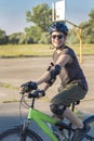 Young teenager in a helmet and a black T-shirt rides a bicycle on the sports ground. Summer and vacation. Health and Sports