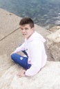 Young teenager male sitting on breakwaters while looking at camera Royalty Free Stock Photo