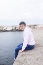 Young teenager male sitting on breakwaters while looking at camera Royalty Free Stock Photo