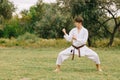 Young teenager practicing karate on a park background. Fighting technique concept. Copy space. Royalty Free Stock Photo