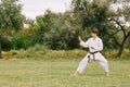 Young teenager practicing karate on a park background. Fighting technique concept. Copy space. Royalty Free Stock Photo