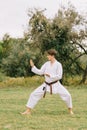 Young teenager practicing karate on a park background. Fighting technique concept. Copy space. Royalty Free Stock Photo