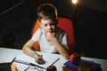 Young teenager schoolboy at the table doing homework in the dark room Royalty Free Stock Photo