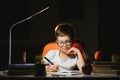 Young teenager schoolboy at the table doing homework in the dark room Royalty Free Stock Photo