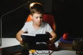 Young teenager schoolboy at the table doing homework in the dark room Royalty Free Stock Photo