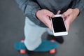A young teenager is standing on a penny board with a phone in his hands.