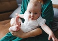 A young gentle happy mother hugs her newborn baby, smiling, sitting at home on the couch. Royalty Free Stock Photo