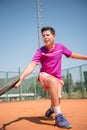 Young tennis player playing backhand and glide on a sunny day.